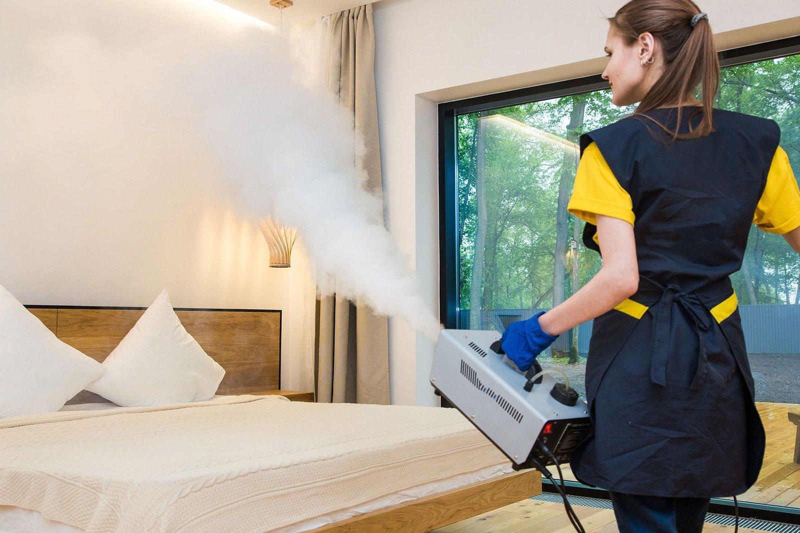 Eine Mitarbeiterin behandelt ein Hotelzimmer mit einem Kaltvernebelungsgerät
