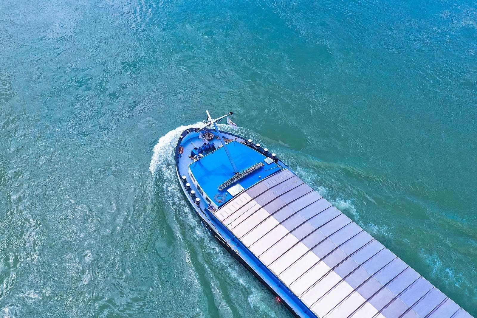 Bateau fluvial bleu sur une voie navigable, vu du dessus